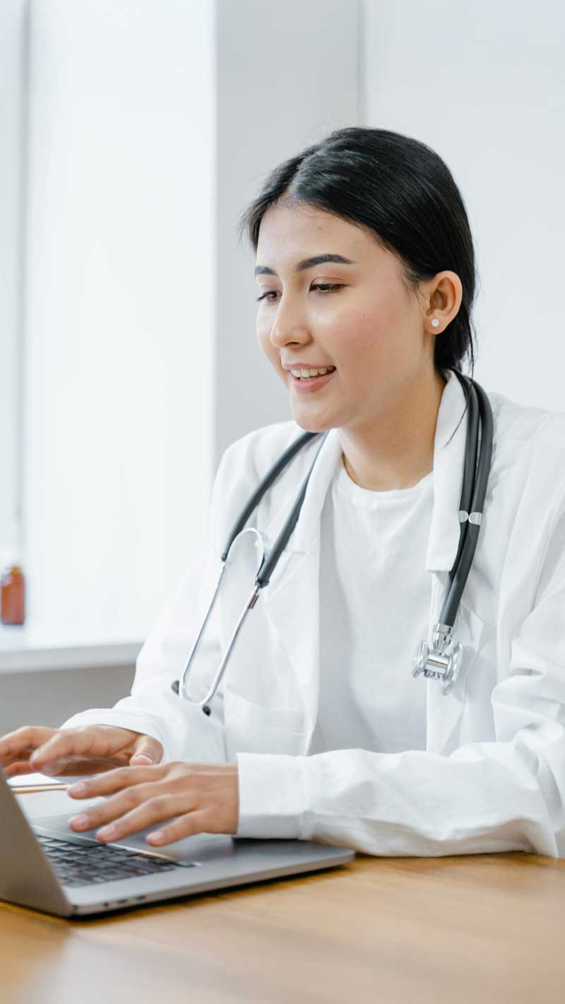female doctor in a labcoat using a laptop